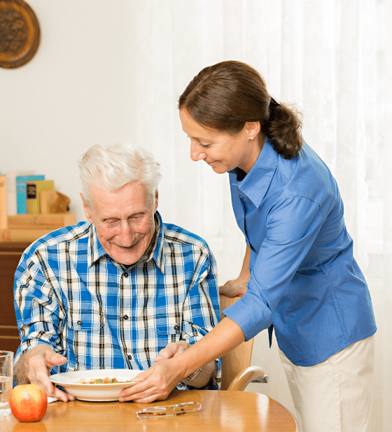 Providing essential personal care services, including meal preparation and feeding assistance to a smiling senior.